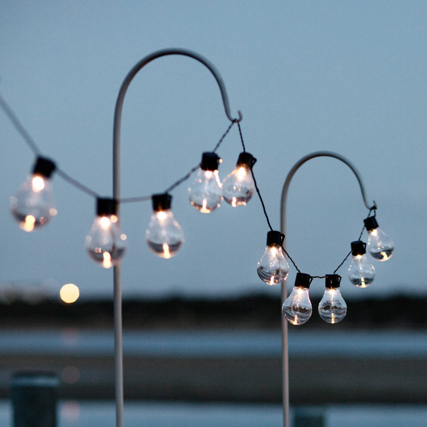 Diese Party-Lichterketten aufgehängt an Schäferstäben ist ein richtiger Hingucker. Finde im dazugehörigen Blog Post heraus welche Beleuchtungsmethode für den Einsatz in deinem Garten besser geeignet ist. Batterie- oder Solarbetrieb.
