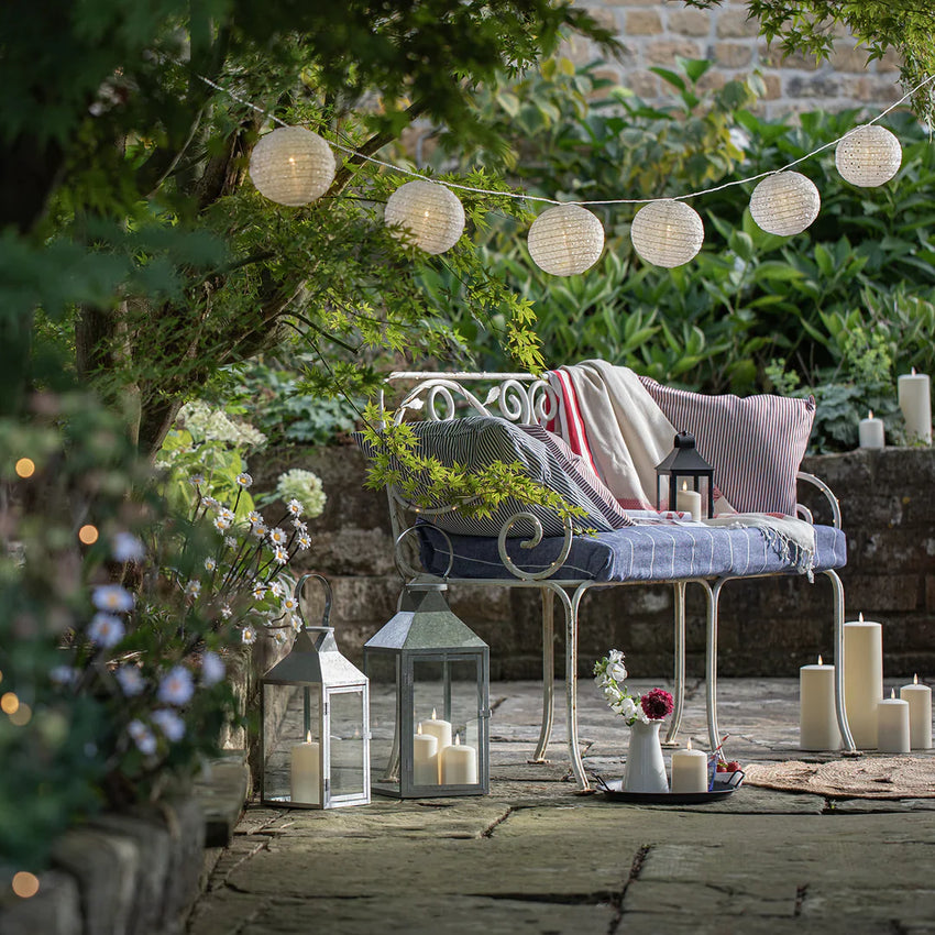 Mit LED Kerzen, Laterne und kleinem LED Brunnen dekorierter Balkon, darüber eine Party Lichterkette mit weißem Kabel