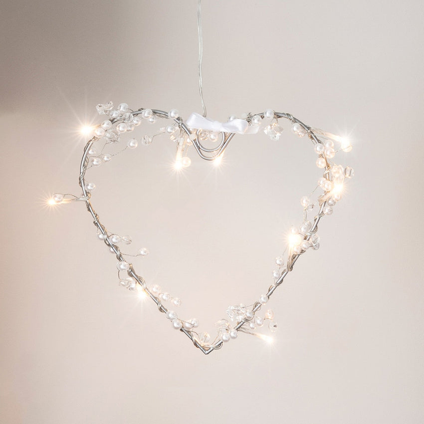 Für den Valentinstag in Rosatönen dekoriertes Sideboard mit LED Kerzen, Herzlichterkette, LED Herz, Luftballons und Prosecco