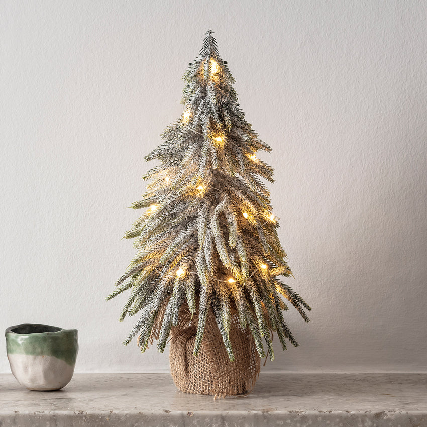 Kleiner warmweiß beleuchteter Weihnachtsbaum auf einem Kaminsims