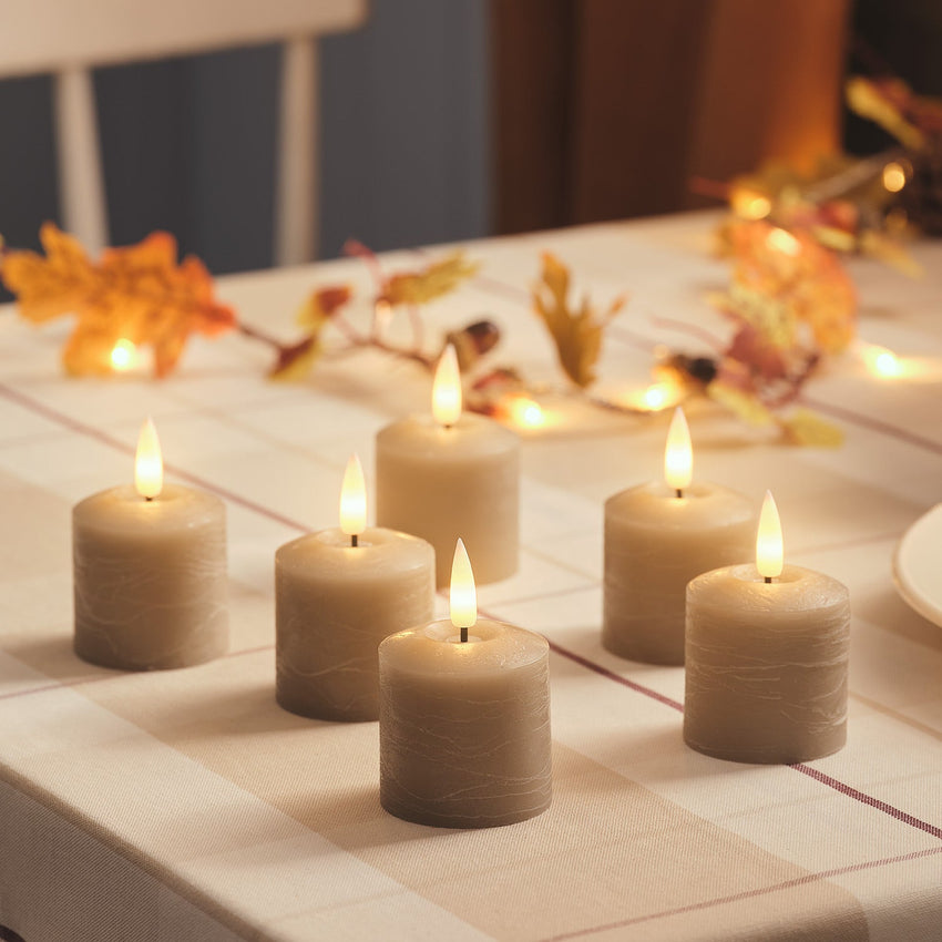 Weiße TruGlow LED-Kerzen mit warm flackernder Flamme auf einem gedeckten Gartentisch mit Blumen