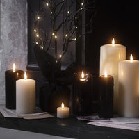 Schwarze LED Kerzen und Halloween-Laterne mit Hexenmotiv auf einer Holzkommode