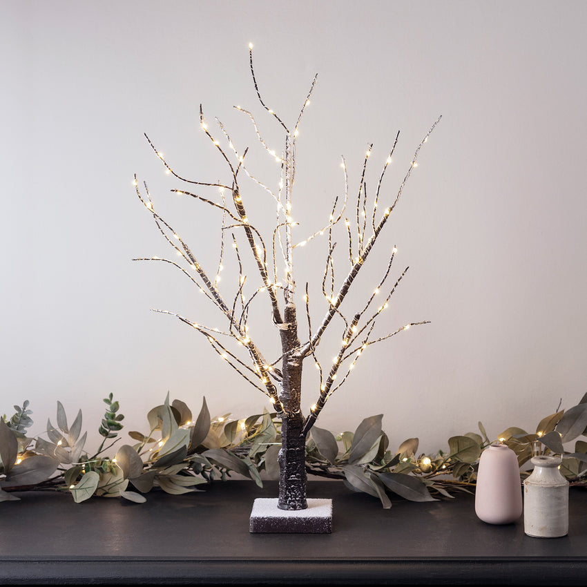 Warmweiß beleuchteter LED Dekobaum auf einer dunklen Holzkommode