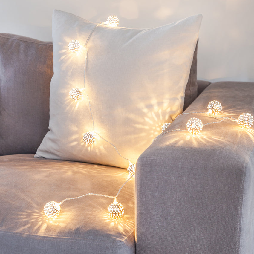 Warmweiß leuchtende marokkanische Kugellichterkette auf einem grauen Sofa