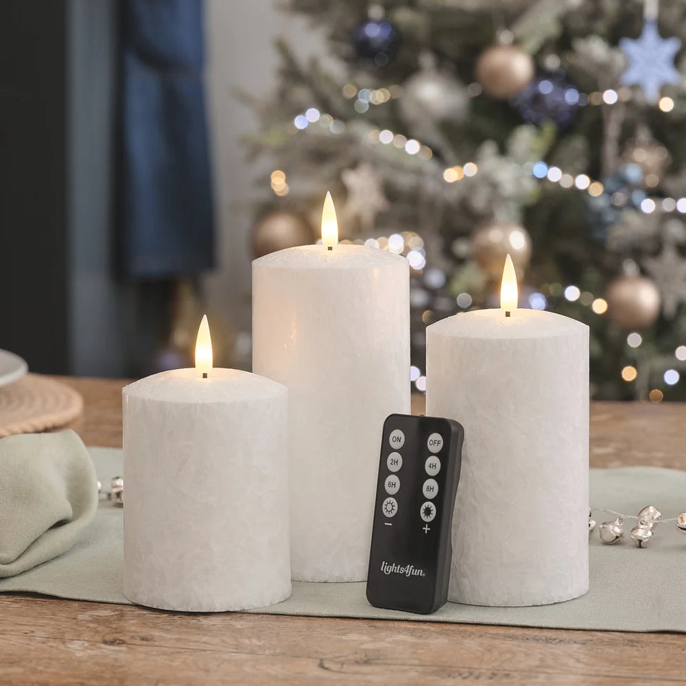 Drei weiße LED-Kerzen mit LED-Flammen, schwarze Fernbedienung mit ON/OFF und Timer-Funktionen (2H, 4H, 6H, 8H) auf Holztisch.