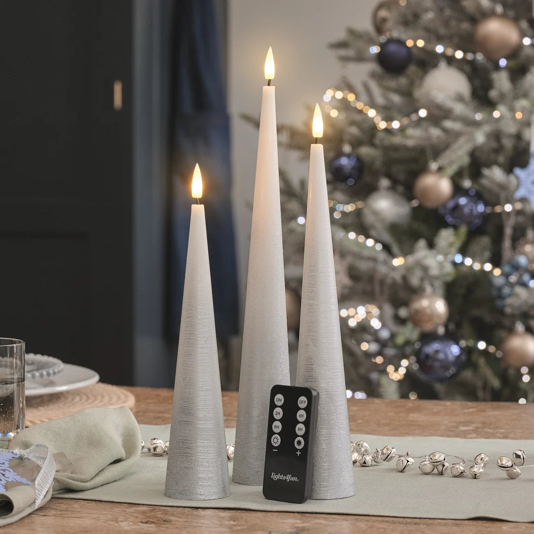 Drei weiße LED-Kerzen in hoher Kegel-Form mit strukturierter Oberfläche, warmweiße LED-Flammen, schwarze Fernbedienung mit ON/OFF und Timer-Funktionen (2H, 4H, 6H, 8H) auf Holztisch.