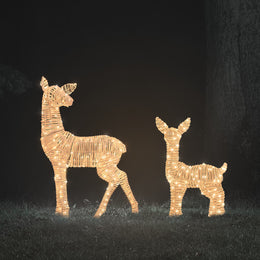 Zwei beleuchtete LED-Rehkitze aus Rattan in warmweißem Licht bei Nacht auf Rasen