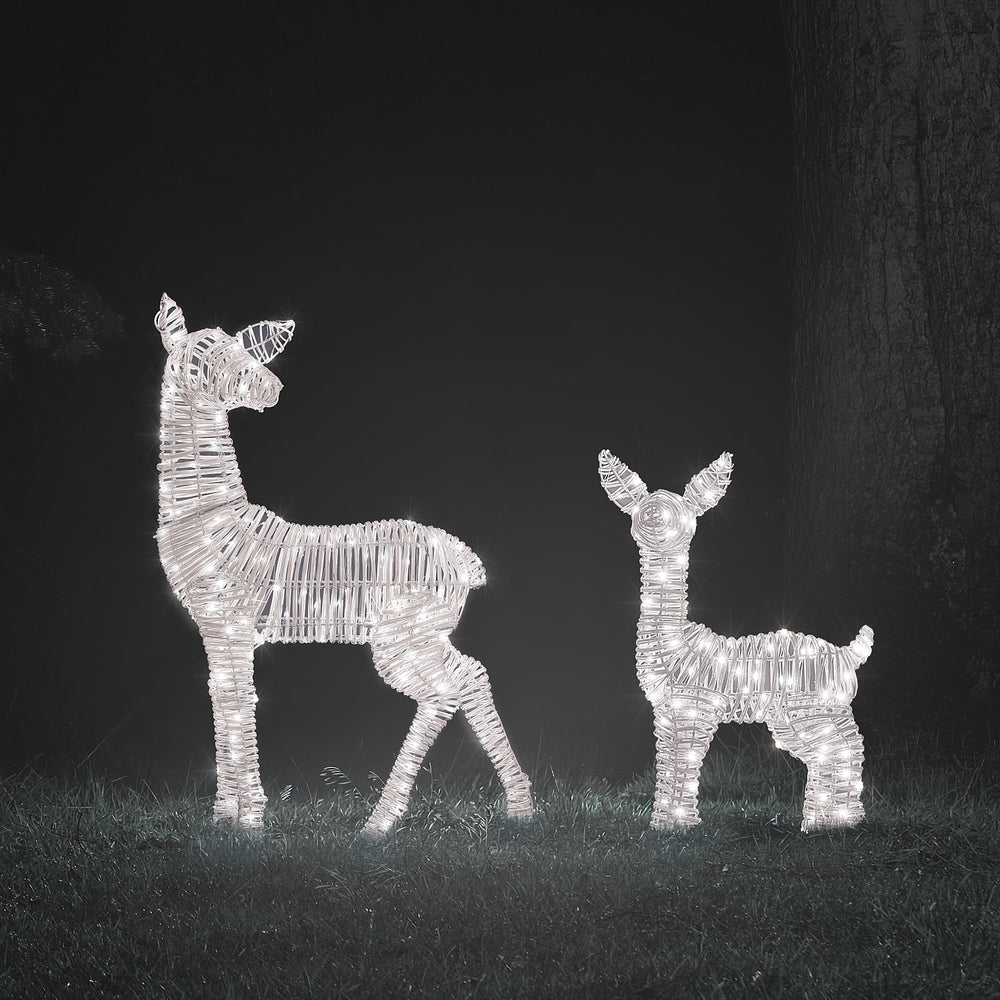 Zwei LED-Rehkitze aus Rattan in weißem Licht leuchtend bei Nacht auf Rasen