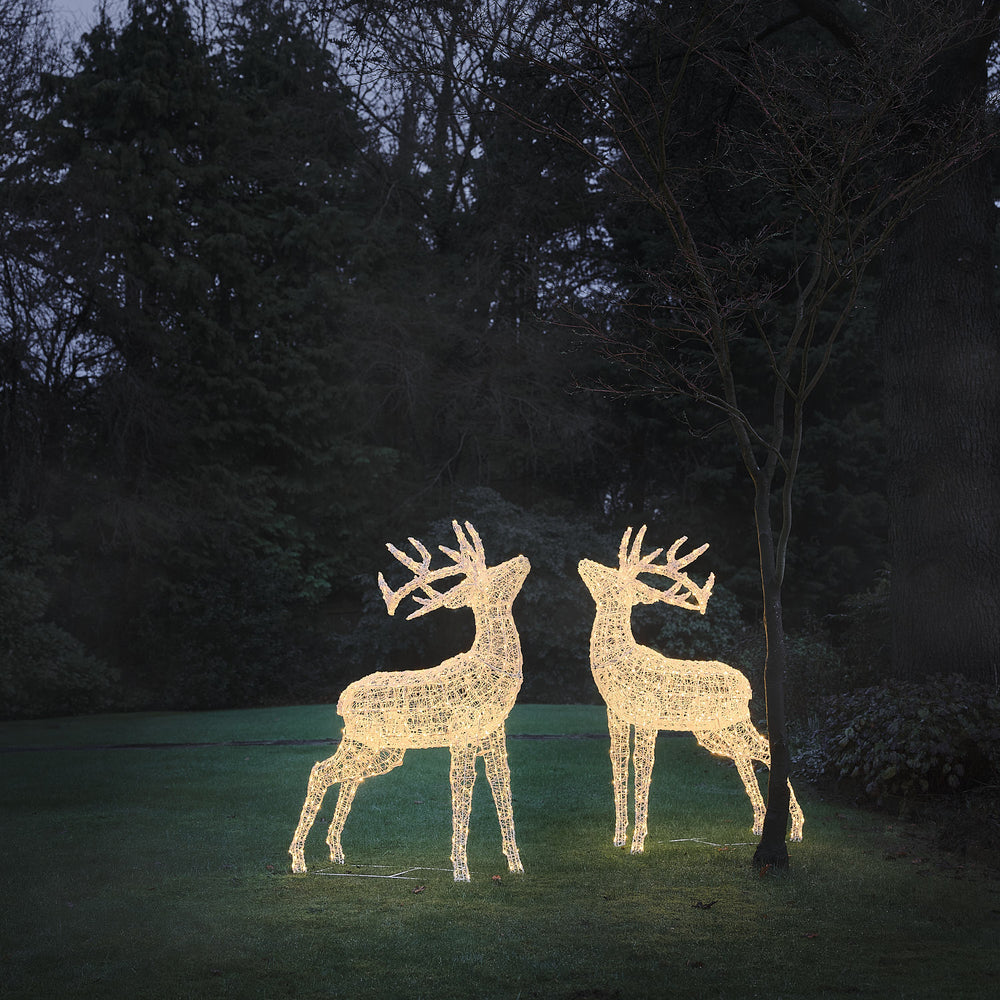 Zwei beleuchtete LED-Hirschfiguren aus weißem Acryl im Garten bei Dämmerung