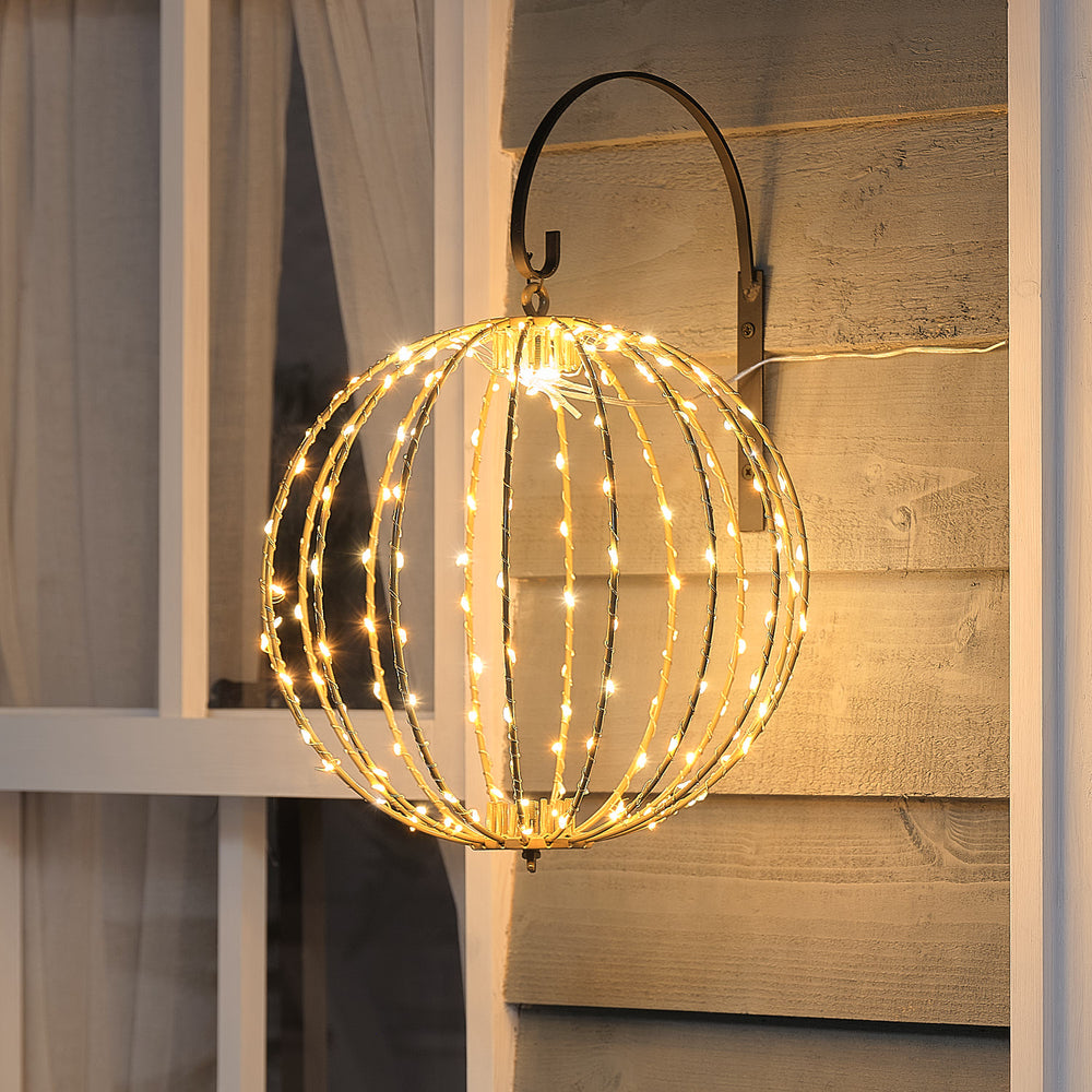 Spektakuläre große hängende LED-Kugel-Dekofigur mit offener Drahtstruktur und warmweißer Beleuchtung, positioniert an schwarzem Metallbogen vor rustikalem braunem Holzhintergrund – festliche hängende Lichtdekoration für Außendekoration, Veranda-Arrangements und weihnachtliche Hausdekorationen mit eleganter geometrischer Form.