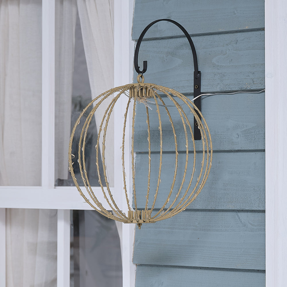 Elegante hängende LED-Kugel-Dekofigur mit offener Drahtstruktur in geometrischem Design, positioniert an schwarzem Metallbogen vor hellblauem Holzwand-Hintergrund – dekorative Hängeform für Außendekoration und klassische Weihnachtsarrangements mit modernem Drahtdesign.