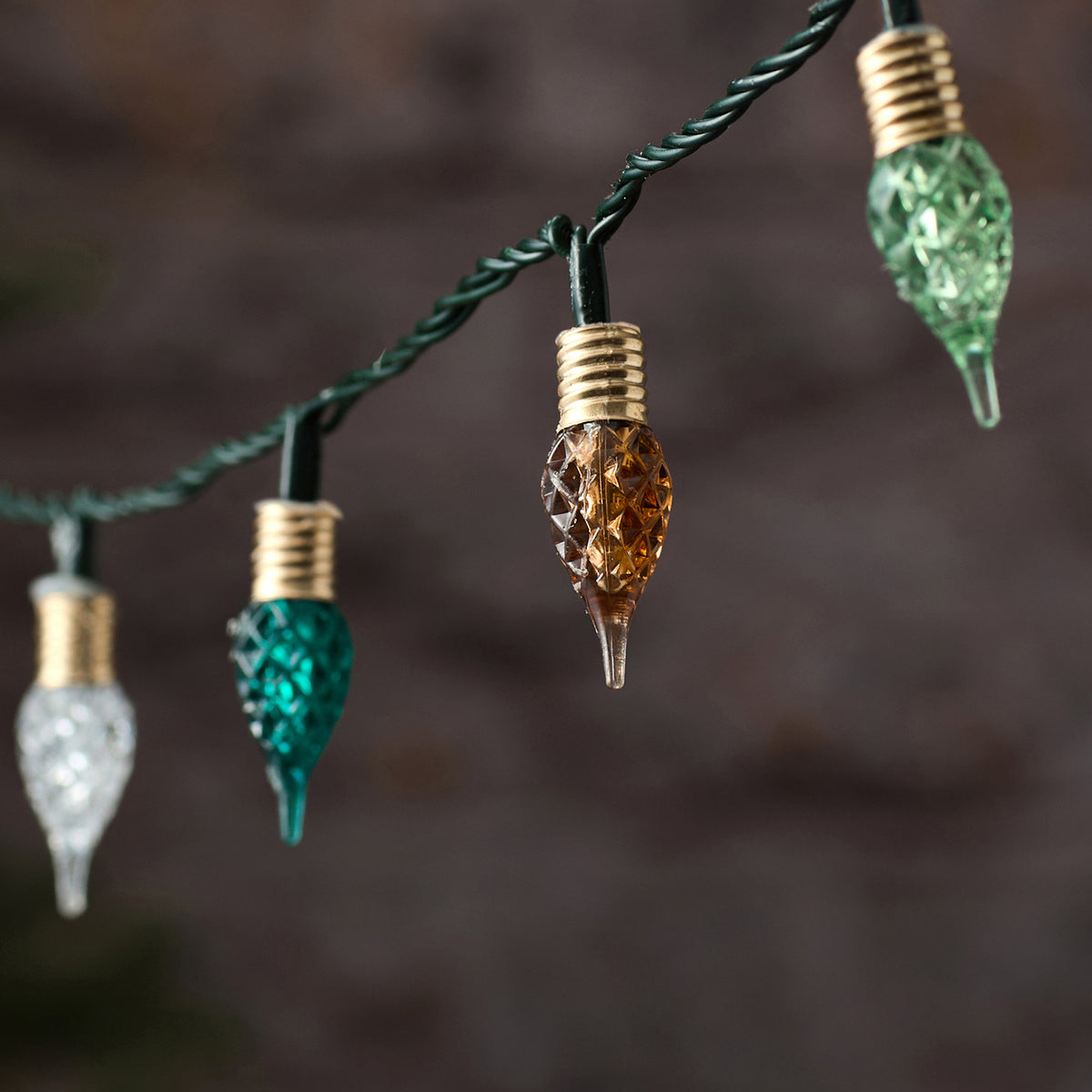 Elegante mehrfarbige LED-Lichterkette mit schwarzem Draht und hängenden Tropfen-Anhängern in verschiedenen Farben (Orange, Gold, Grün, Weiß), arrangiert vor dunklem Bokeh-Hintergrund – luxuriöse Lichterkette für gehobene Außen-Weihnachtsarrangements und spektakuläre Premium-Dekorationen.