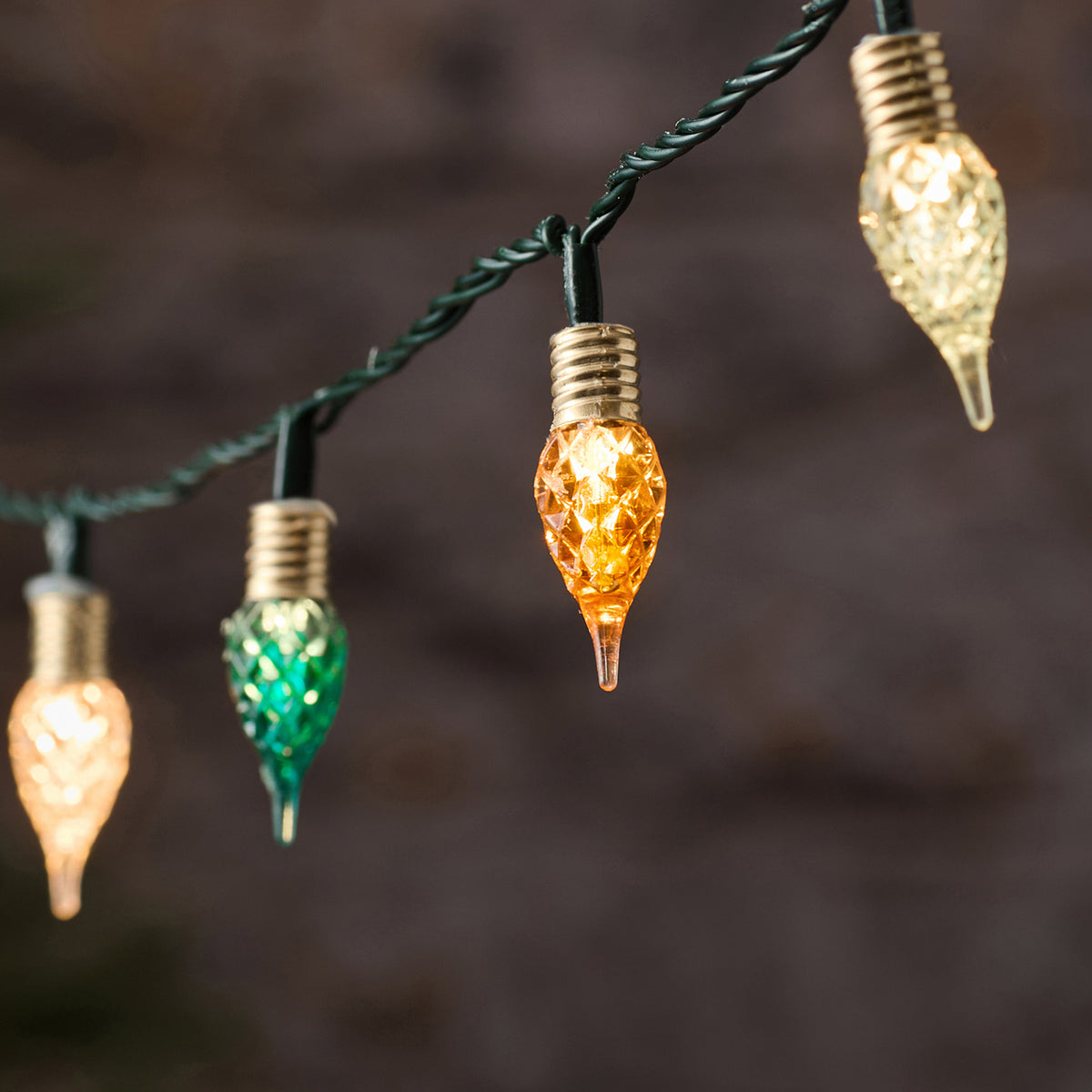 Festliche LED-Lichterkette mit schwarzem Draht und mehrfarbigen hängenden Tropfen-Dekofiguren (Gold, Grün, Orange, Weiß, Blau), positioniert vor dunklem atmosphärischem Hintergrund – Premium-Lichterkette mit Farbmix für spektakuläre Außen-Weihnachtsdisplays und elegante Garten-Dekorationen.