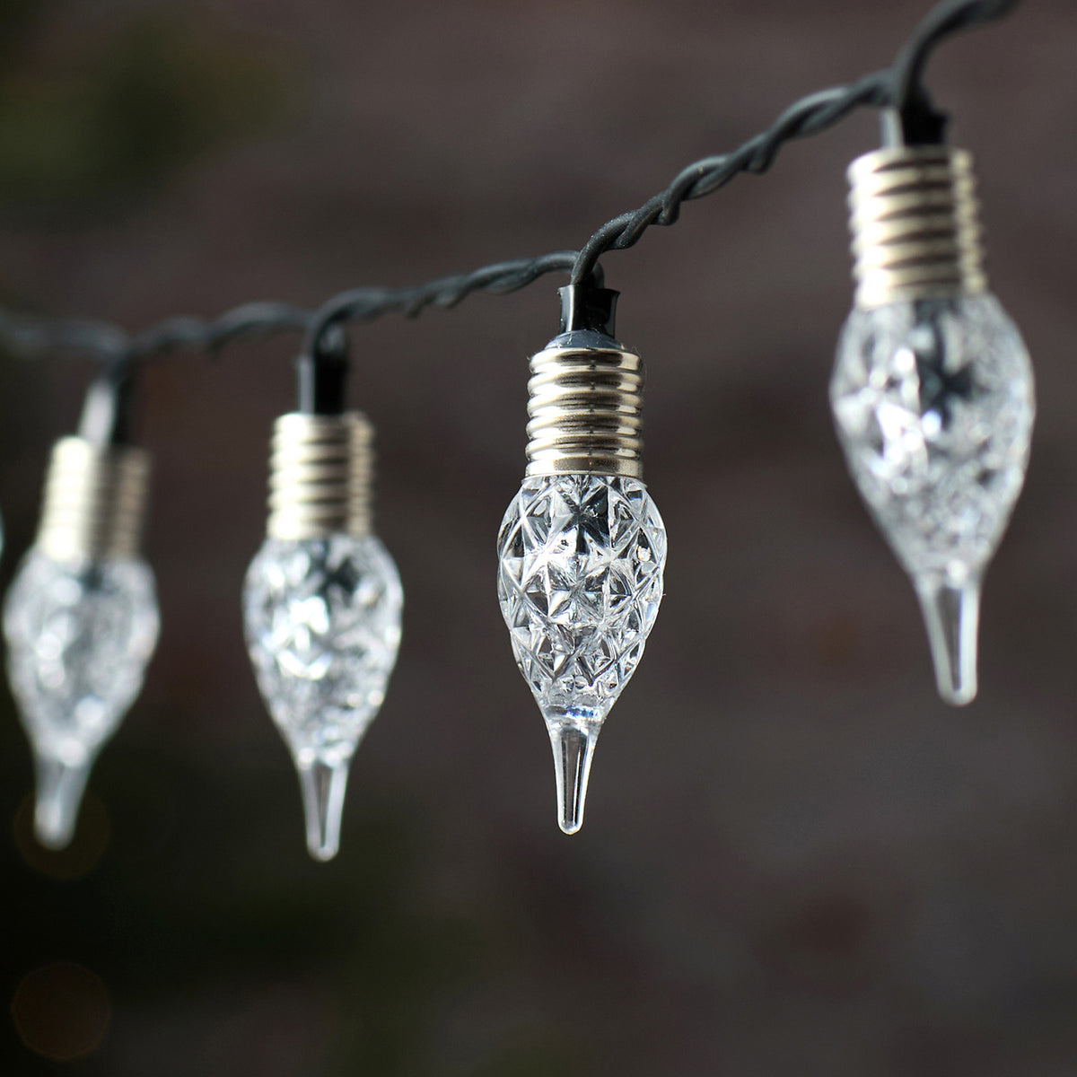 Elegante mehrfach-Tropfen LED-Lichterkette mit schwarzem Draht und hängenden kristallinen Dekofiguren in unterschiedlichen Längen und Champagner-Gold-Färbung, arrangiert vor dunklem Bokeh-Hintergrund – luxuriöse Premium-Lichterkette für gehobene Außen-Weihnachtsarrangements und spektakuläre Fassaden-Dekorationen.