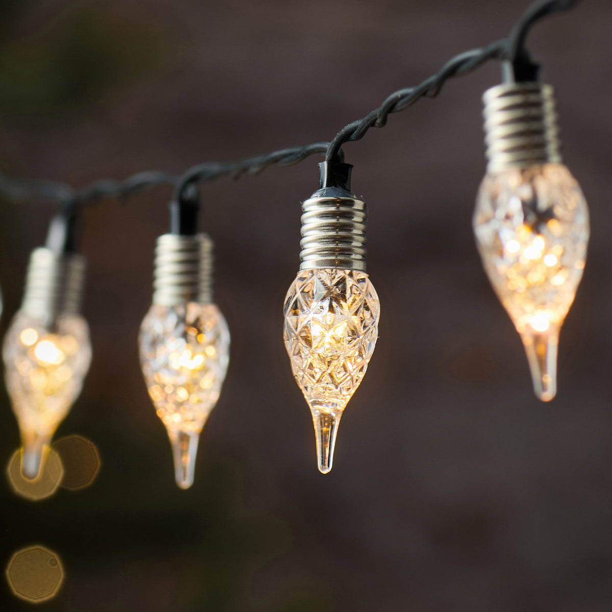 Spektakuläre LED-Lichterkette mit schwarzem Draht und mehreren hängenden kristallinen Tropfen-Dekofiguren in Champagner-Gold-Tönen mit warmweißer LED-Beleuchtung, positioniert vor dunklem atmosphärischem Hintergrund – Premium-Lichterkette für spektakuläre Außen-Weihnachtsdisplays und elegante Garten-Dekorationen.