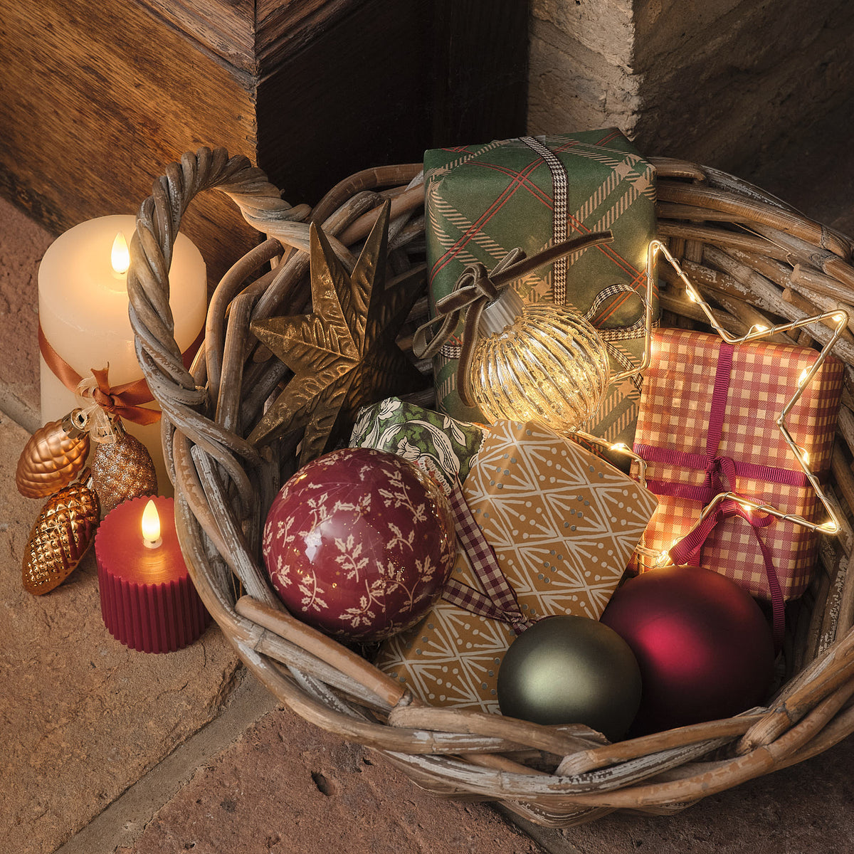 Weidenkorb mit Weihnachtskugeln und Kerzen in warmem Lichterglanz.