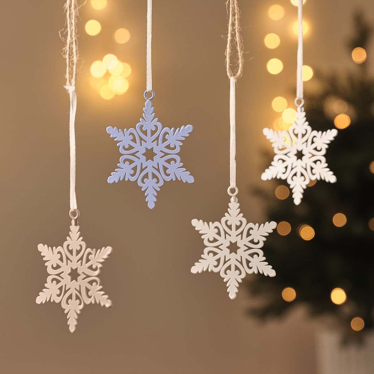 Weiße Schneeflocken-Anhänger mit filigranem Muster, hängend vor Lichterglanz.