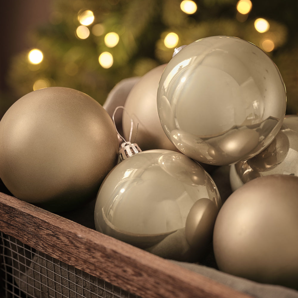 Weihnachtskugeln in matter und glänzender Optik in Holzkiste vor Lichterglanz.