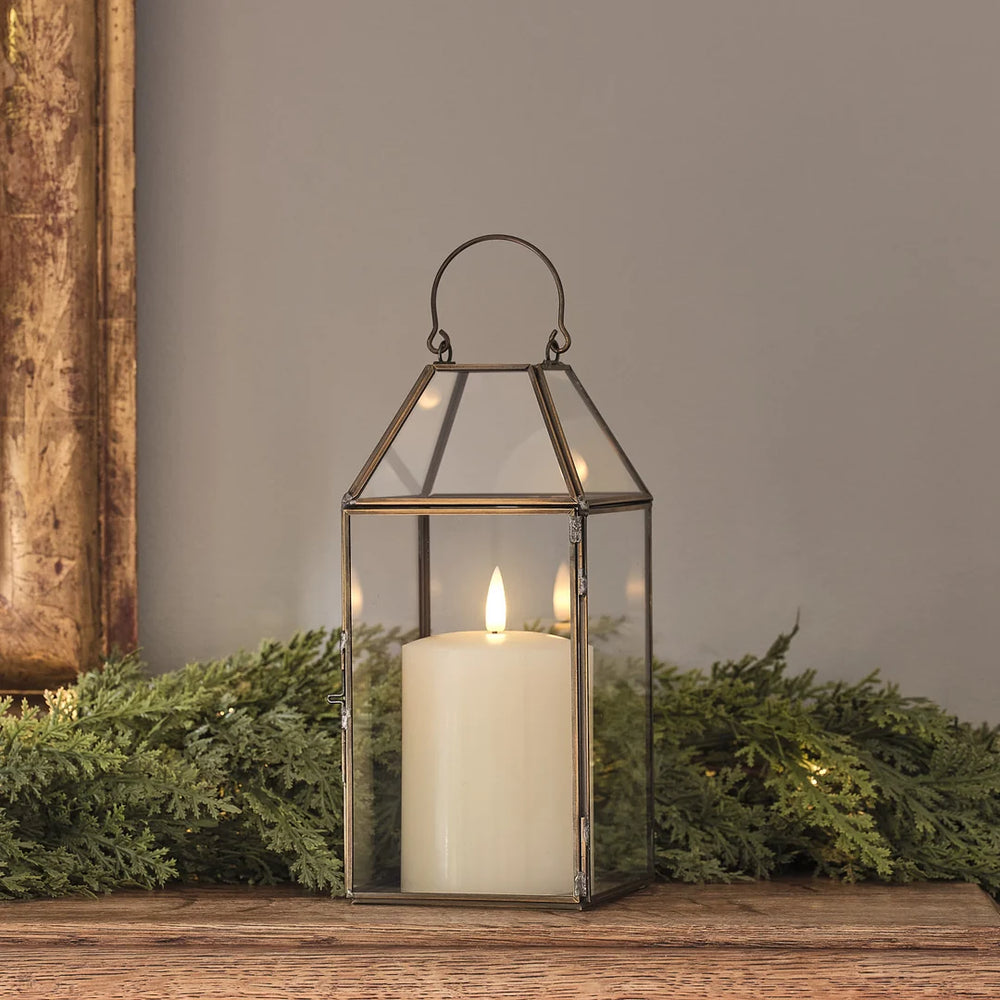 "Goldene Metall-Laterne mit LED-Kerze auf Holztisch vor Tannengrün.