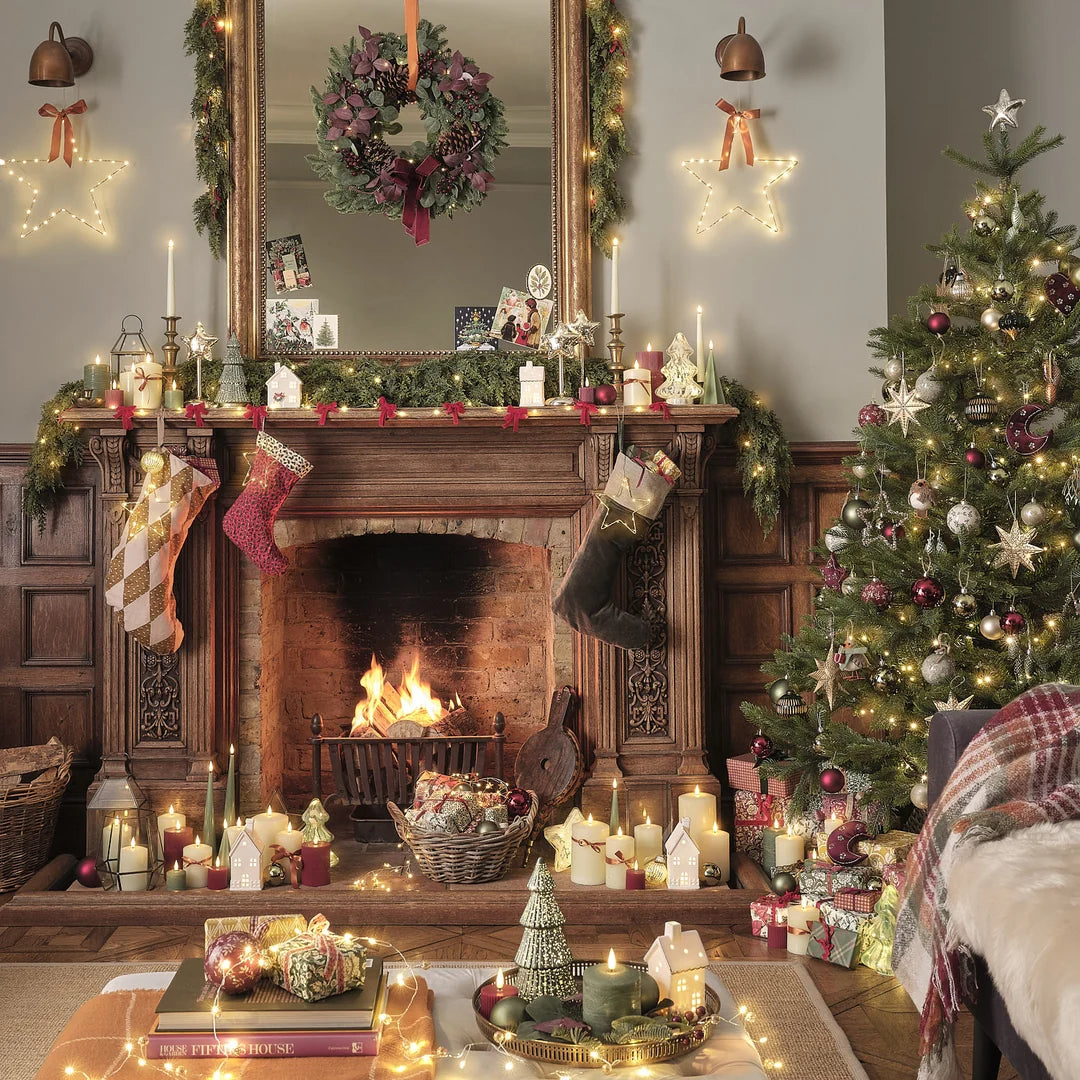 Weihnachtlich dekoriertes Wohnzimmer mit Kamin, Kranz und geschmücktem Baum.