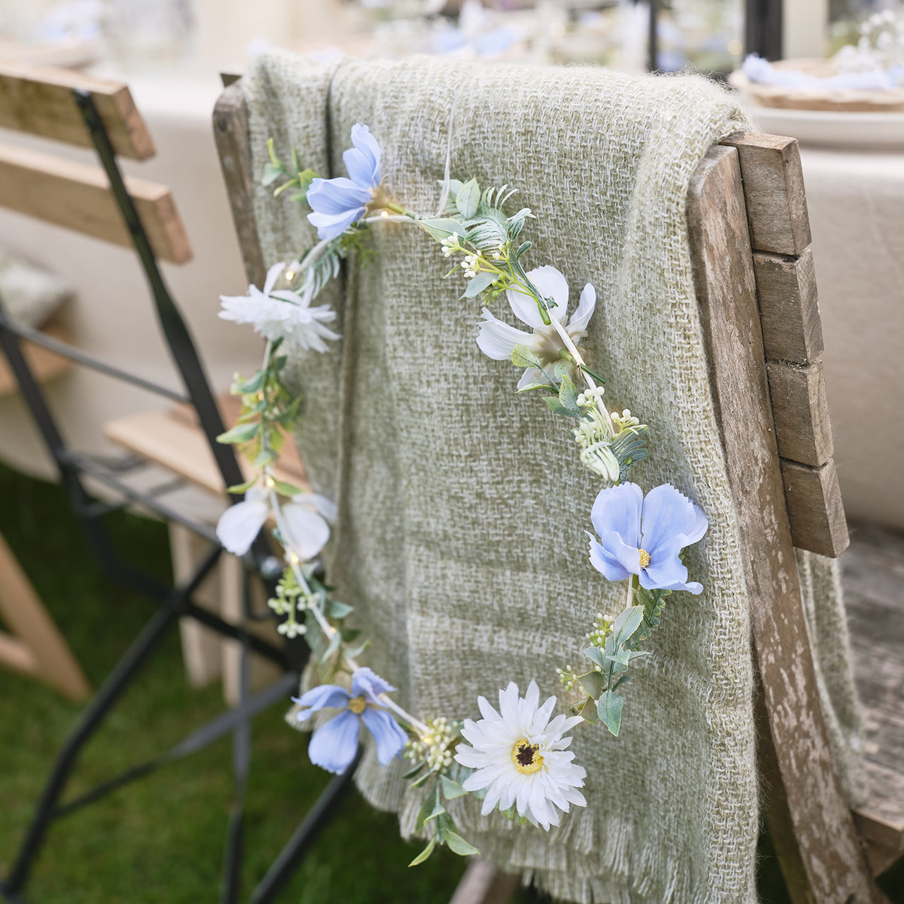 Weißer / blauer LED-Blumenkranz mit warmweißen Mikro-LEDs & Timer auf einem Stuhl