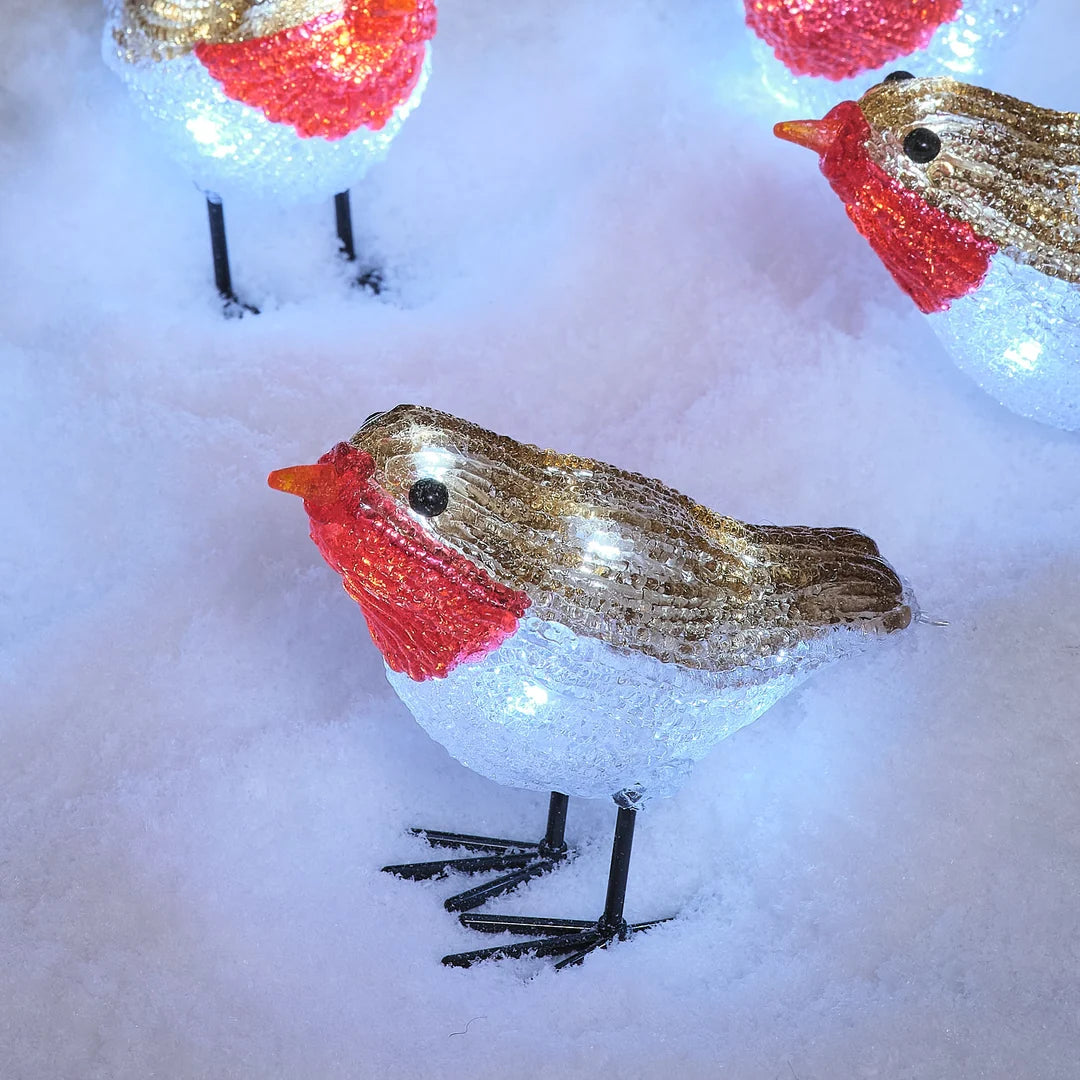 Detailansicht leuchtender LED-Rotkehlchen-Figur im Schnee.