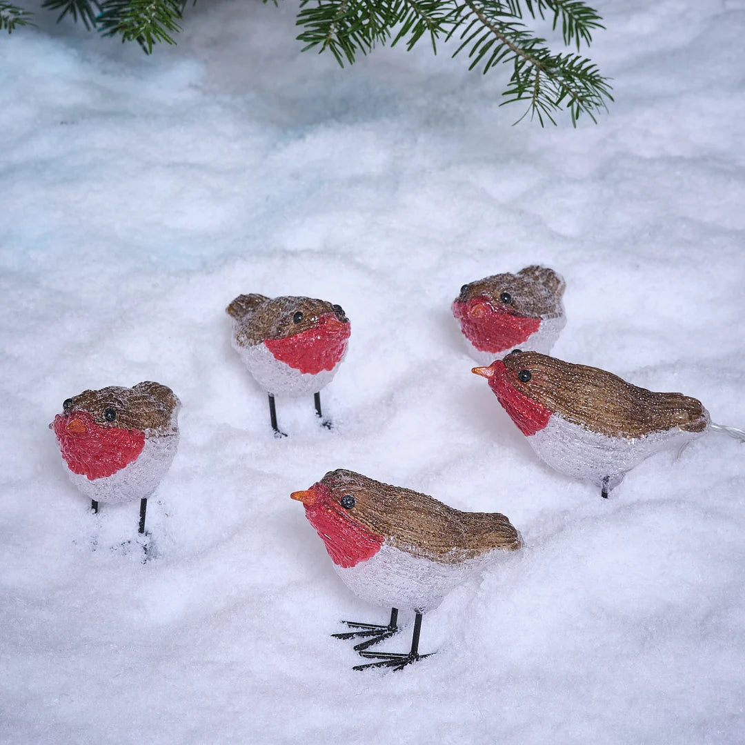 LED-Rotkehlchen-Figuren im Schnee vor Tannengrün.