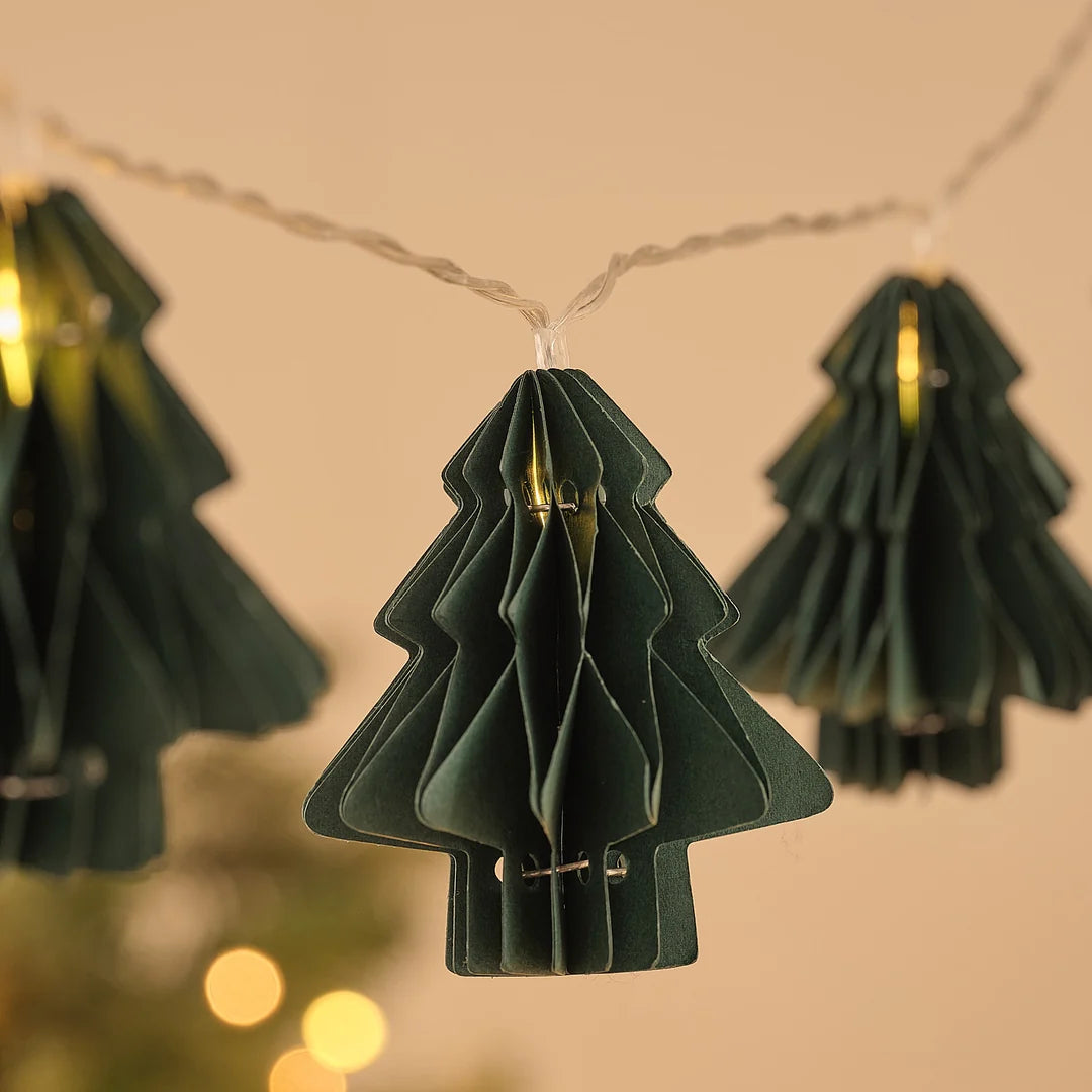 Detailansicht grüner Papier-Tannenbaum-Anhänger an Lichterkette.