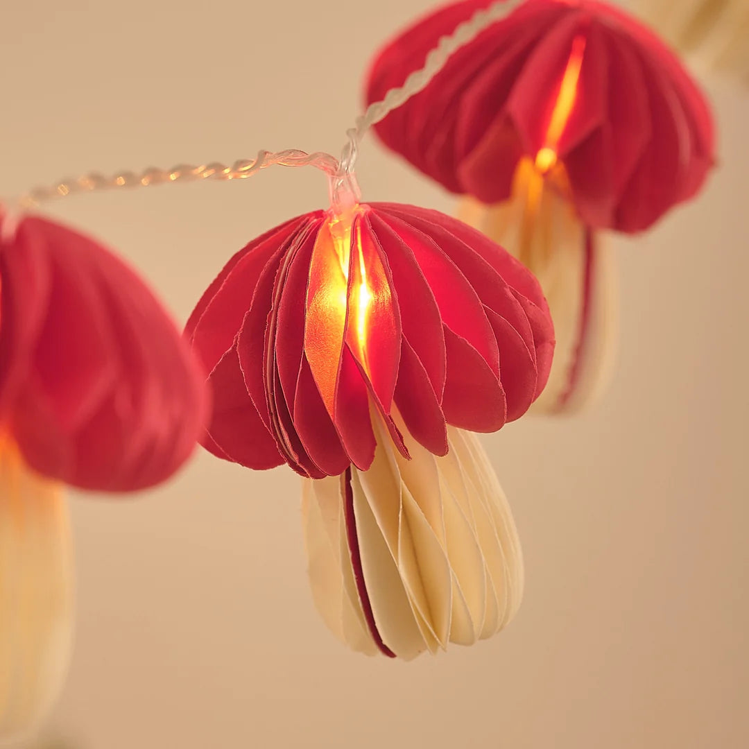 Detailansicht roter Papier-Pilz-Anhänger an Lichterkette.
