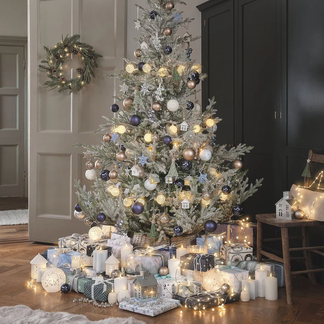 Weihnachtlich dekoriertes Wohnzimmer mit geschmücktem Baum, Kranz und Geschenken.