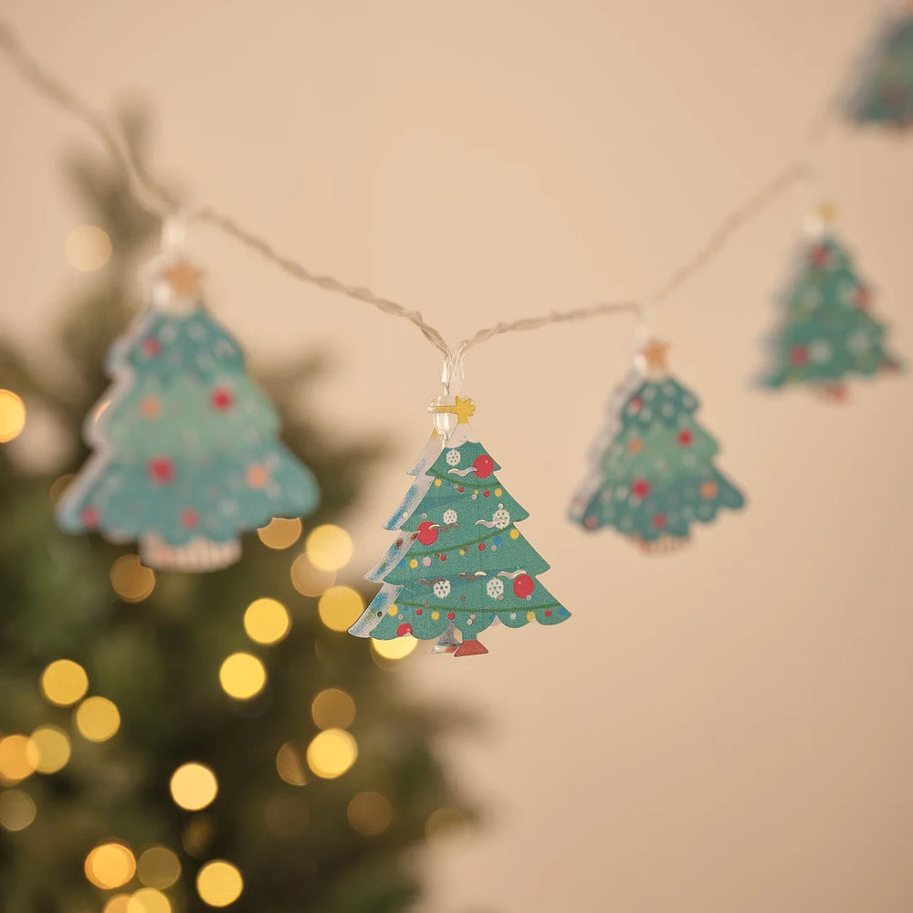 Lichterkette mit mehreren Tannenbaum-Anhängern vor Tannengrün.