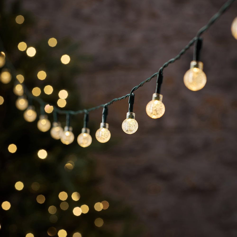 Zweifarbige LED-Lichterkette Bubble Ball mit warmweiß leuchtenden Kugeln im Garten