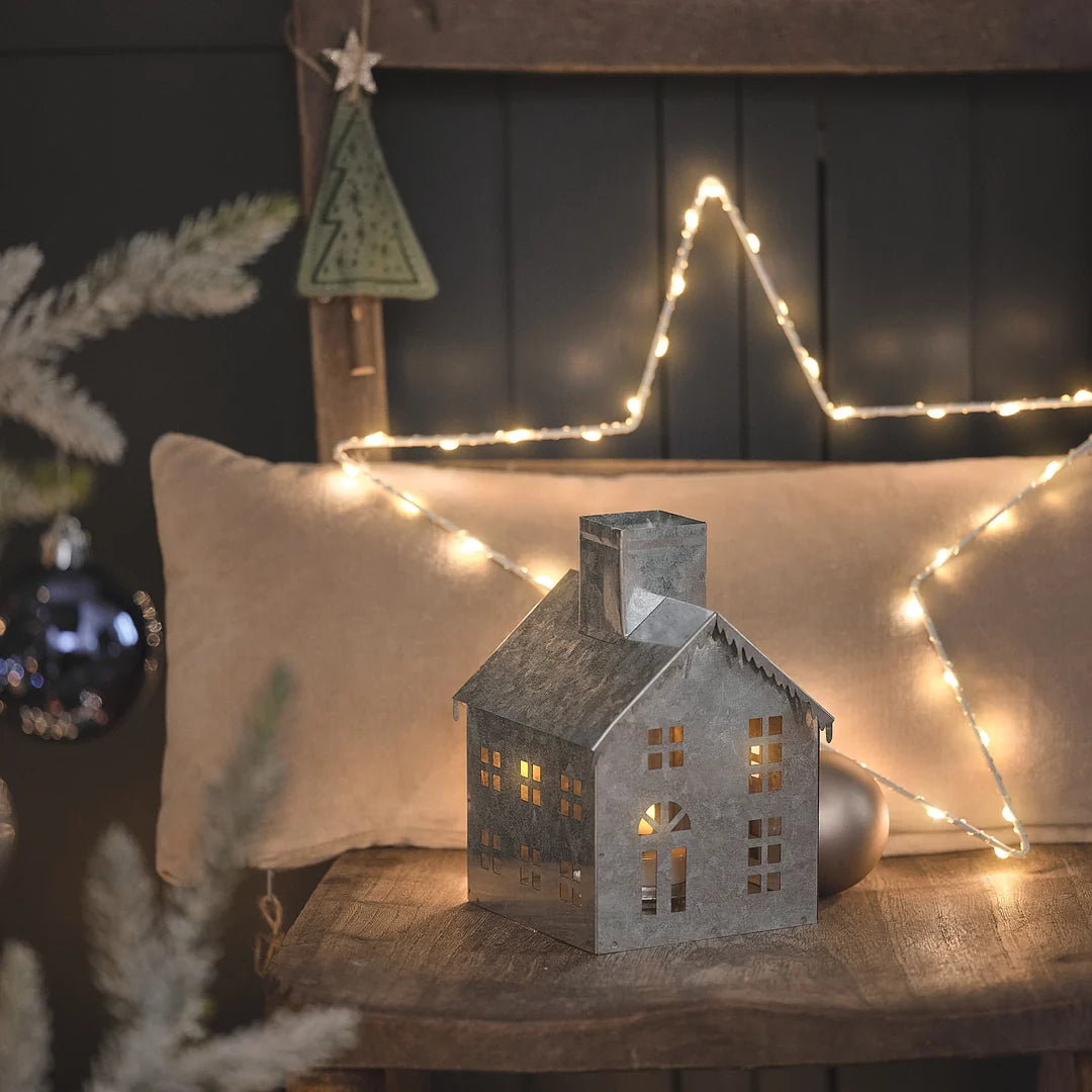 Festliches beleuchtetes Weihnachtshaus mit warmweißen LED-Lichtern, dekoriert mit leuchtender LED-Stern-Girlande und elegant gestylter Weihnachtsszene mit Tannenbaum-Silhouetten und Bokeh-Beleuchtung im Hintergrund – Premium-LED-Dekofigur für atmosphärische Weihnachtsdisplays und gehobene Festdekoration.