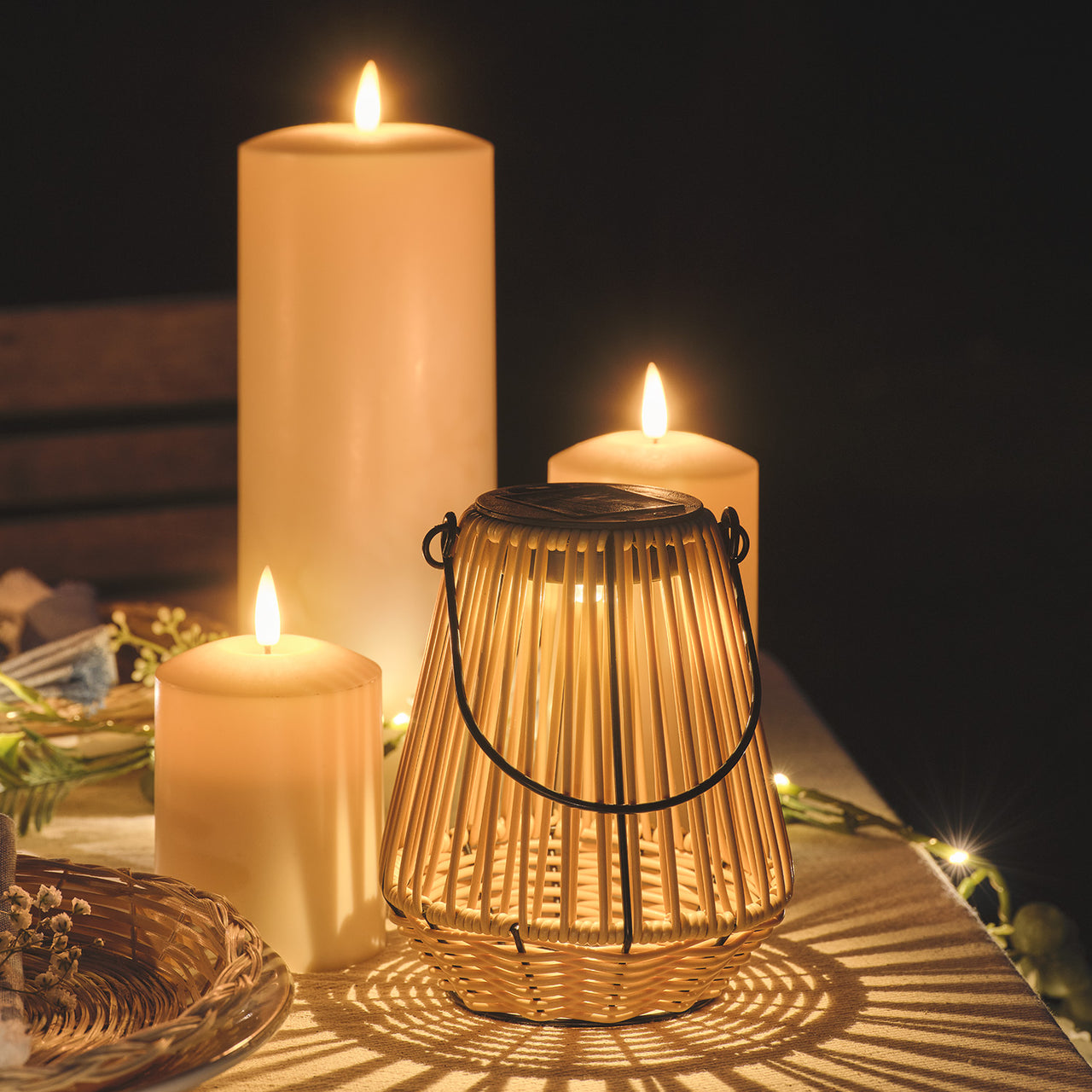 Hygge Solar-Laterne in Rattanoptik mit warmweißer LED neben Kerzen