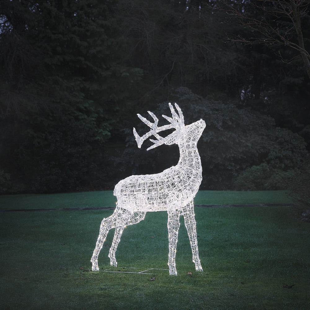 Solar-LED-Hirsch mit bicolor LEDs in weißer Lichtfarbe auf grünem Rasen bei Abenddämmerung