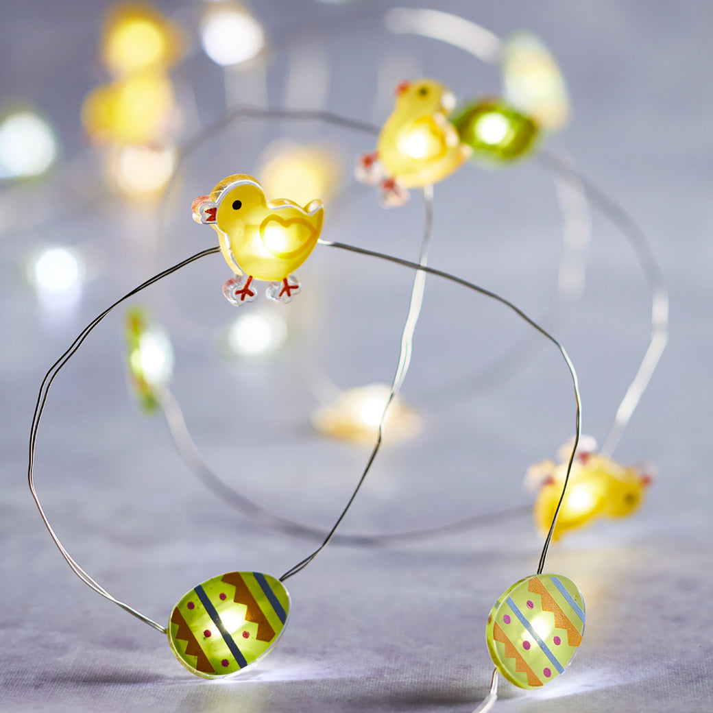 Oster Micro Lichterkette mit Ostereiern und gelben Küken an Draht auf grauem Tisch.