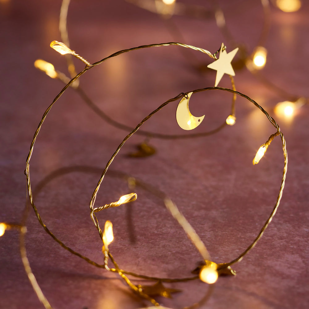 Ramadan Micro Lichterkette mit goldenen Sternen und Monden auf dunklem Holztisch.