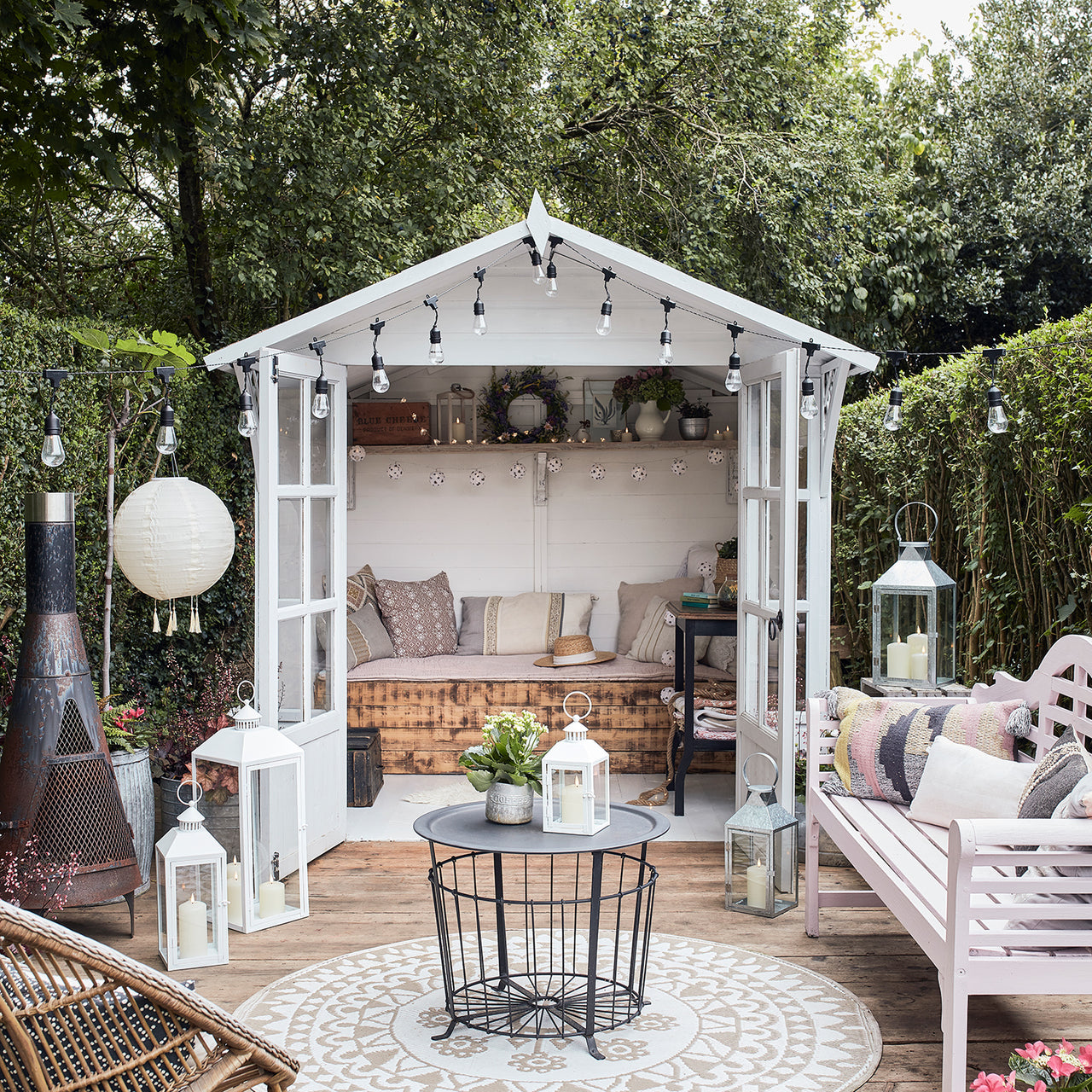 Gartenhaus und Terrasse mit sommerlicher Deko & Leuchtakzenten.