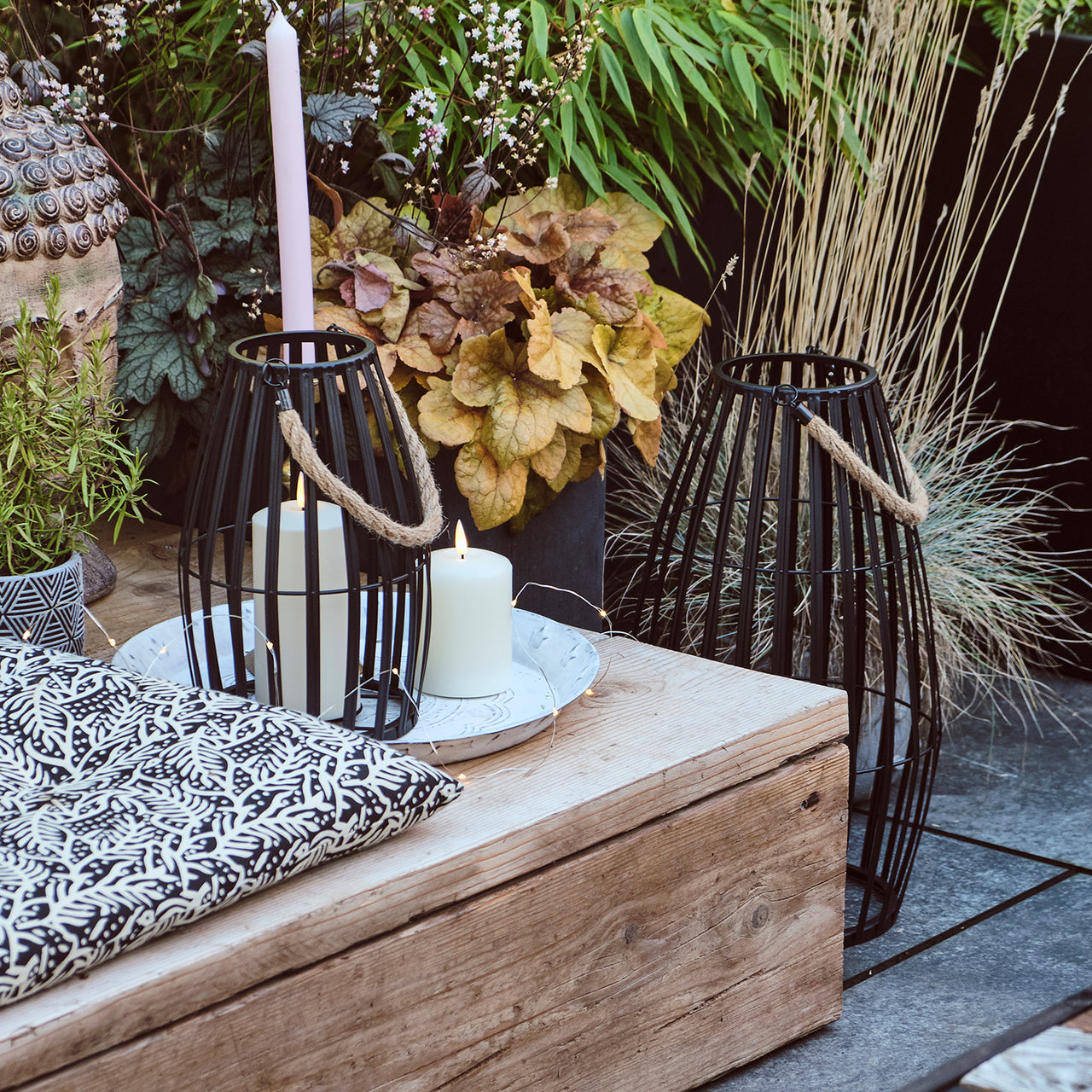 Sitzbank auf Terrasse mit kleiner schwarzer Metall Laterne.