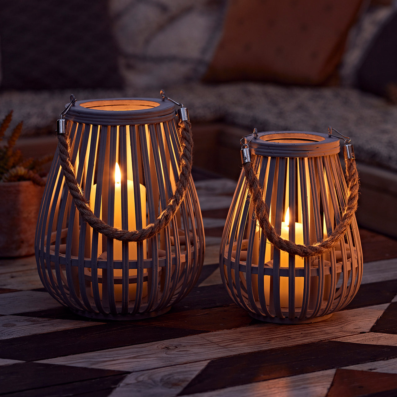 Zwei Holz Laternen mit LED Kerzen außen im Dunkeln mit warmem Licht.