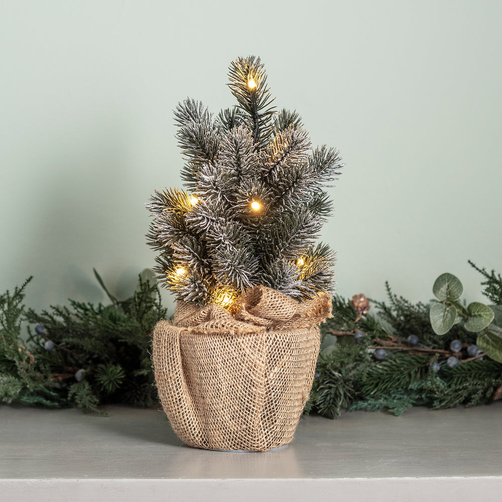 Kleiner Weihnachtsbaum mit LED-Lichterkette und Jutesack.