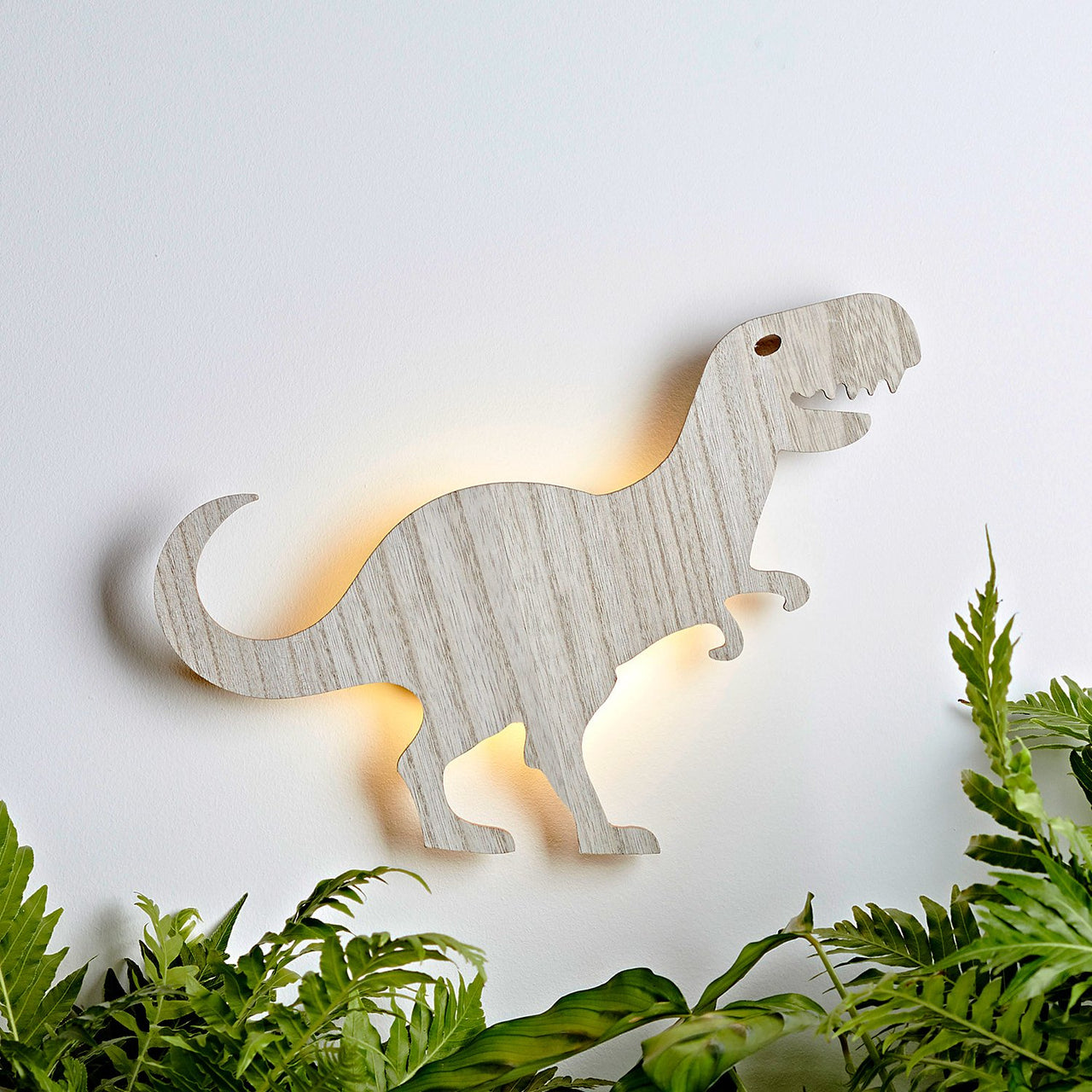 Tyrannosaurus Rex Wandlampe mit Beleuchtung und Pflanzen.