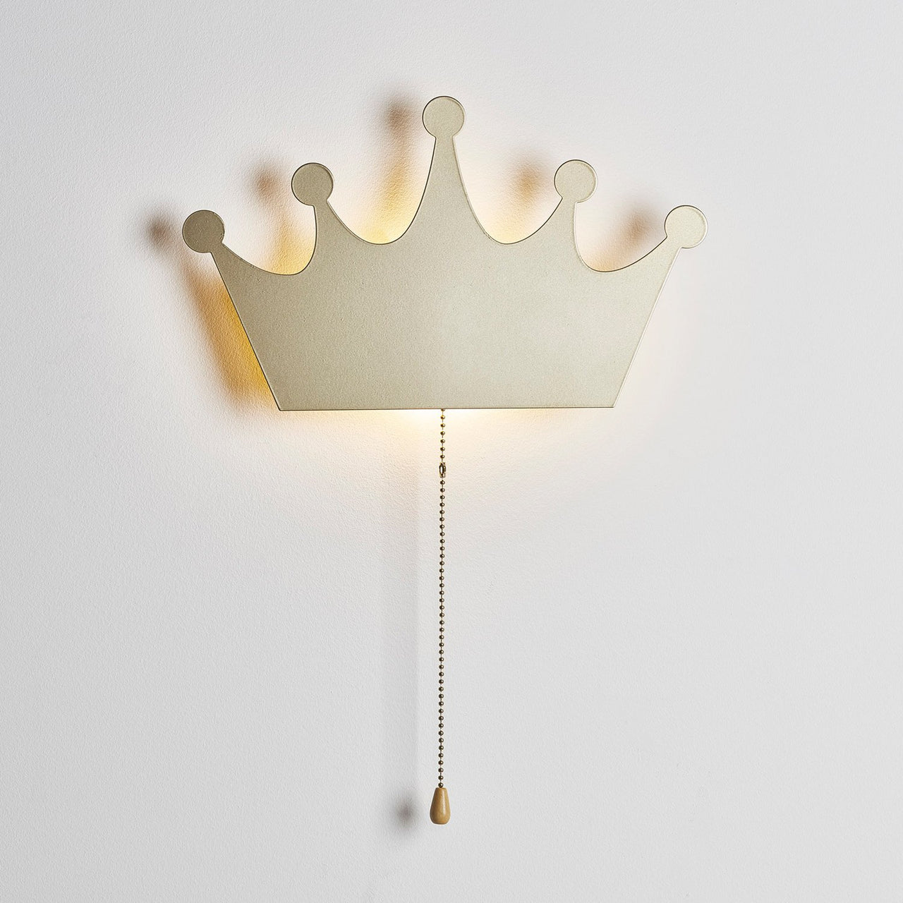 Goldene Wandleuchte in Form einer Krone, angeschaltet.